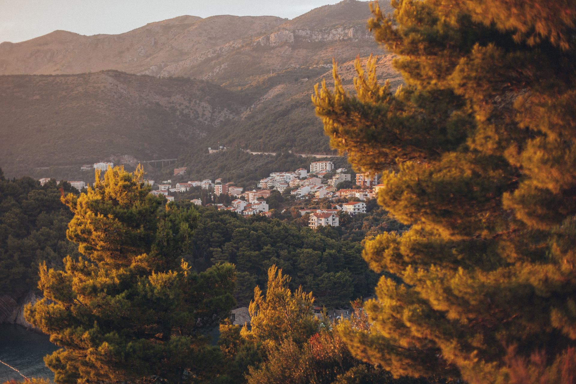 Picturesque mountain town in Montenegro surrounded by vibrant autumn forest at sunset.