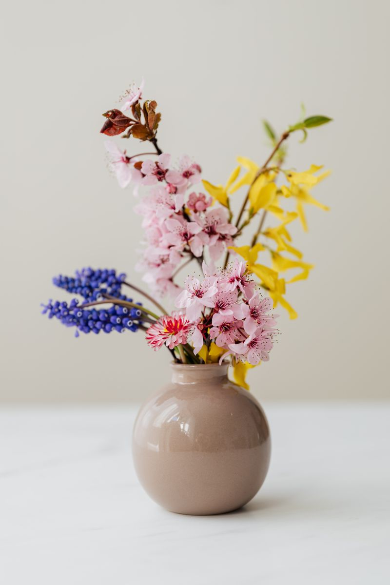 明るいベージュ背景にシンプルに生けられた花々