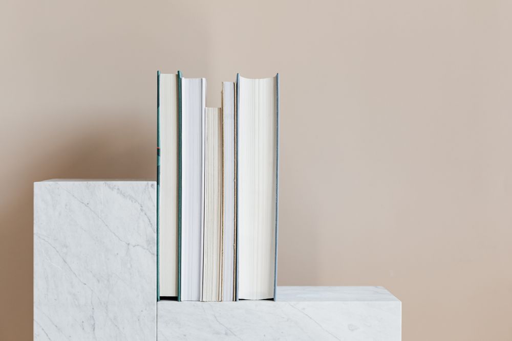 A short row of books standing on a marble ledge, photo by Kaboompics.com on Pexels