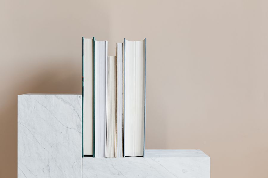 Row of books propped on a marble plinth — photo by kaboompics on Pexels