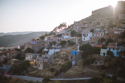 Free Scenic view of a traditional hillside village in Greece at sunset, featuring rustic architecture and lush greenery. Stock Photo