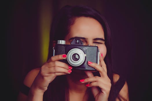 A woman with dark hair uses a vintage camera indoors, embodying nostalgia and creativity.