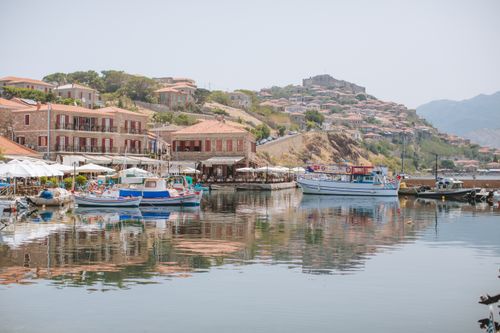 Free Scenic Greek harbor with boats and traditional architecture reflecting on the tranquil water. Stock Photo