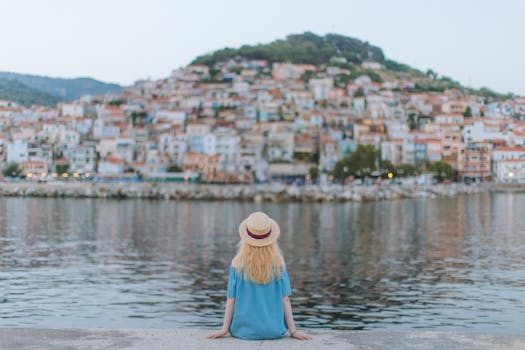 back view of woman in blue dress sitting on the shore