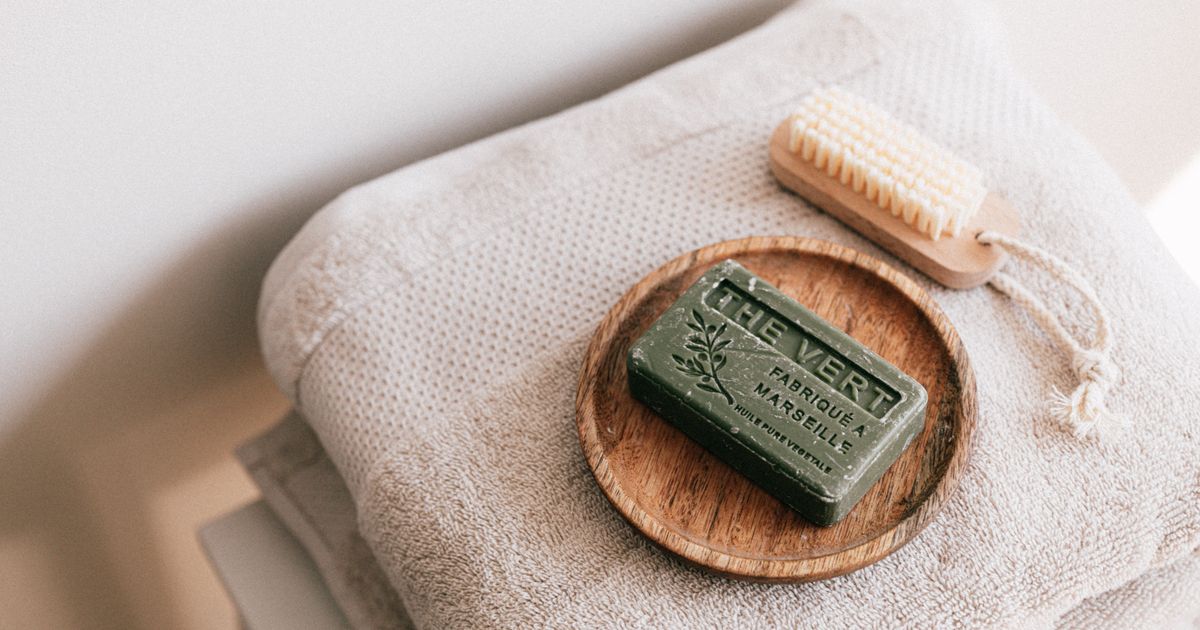 Spa self-care items including folded towels, artisanal soap, and a wooden brush on a clean surface
