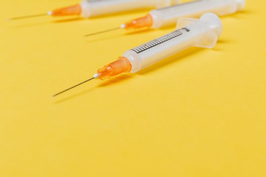 医用一次性注射器的针头没有保护罩，空筒被放置在亮黄色表面上
