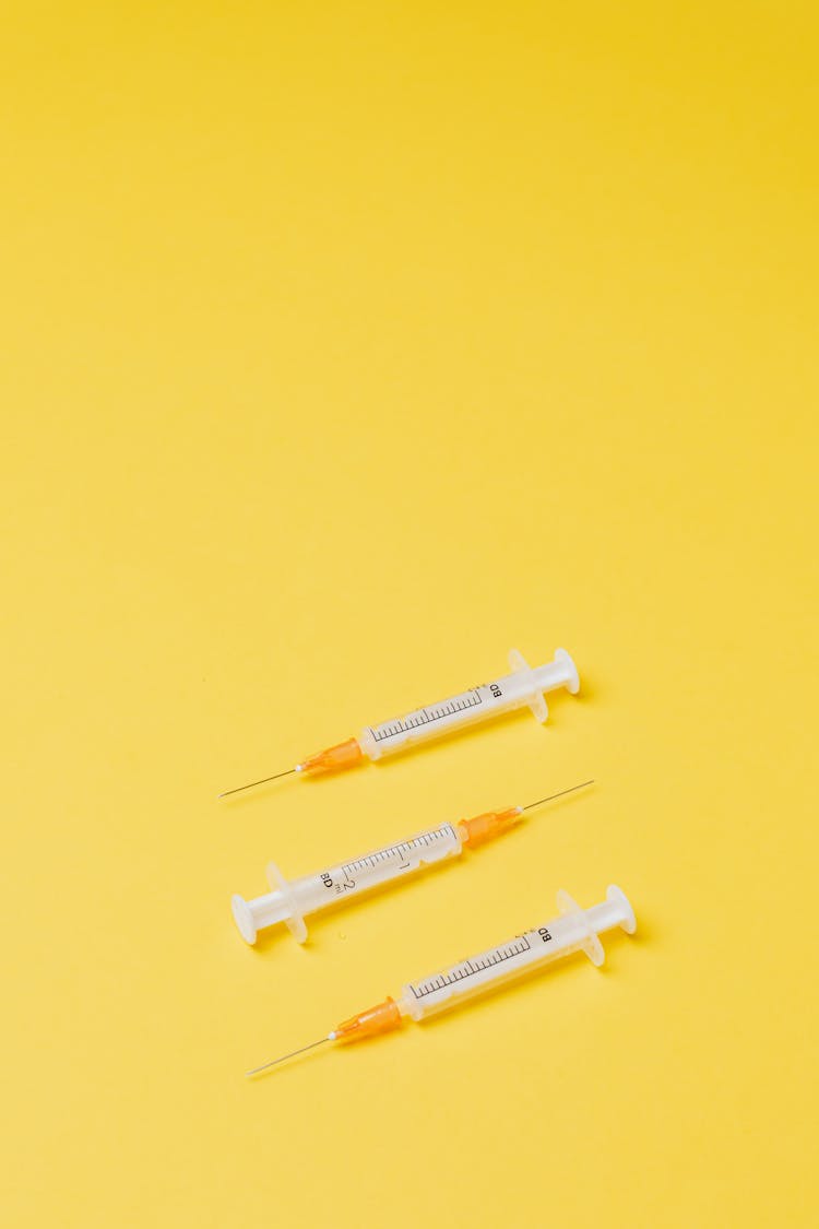 Syringes Without Needle Cover On Yellow Background