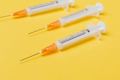 Empty syringe injectors on yellow background
