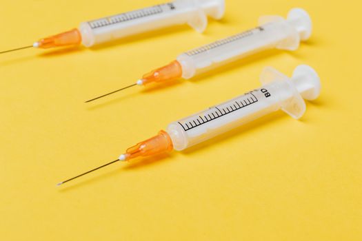 黄色背景充满活力，特写三个注射器，强调健康工具
