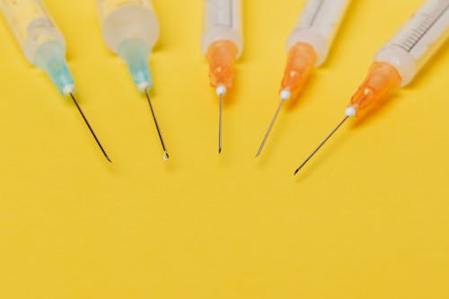 Free Syringe needles with no cover on yellow background Stock Photo