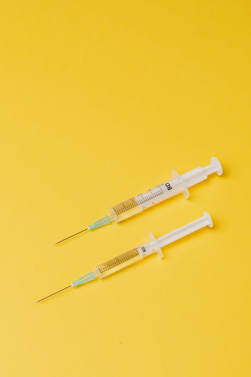 Free Syringes with medical drugs on yellow background Stock Photo