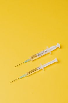 黄色背景上的两个注射器，突出了医疗保健主题
