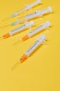 亮黄色表面上摆放着不同尺寸的一次性塑料注射器，里面装有疫苗剂量，没有针头保护罩