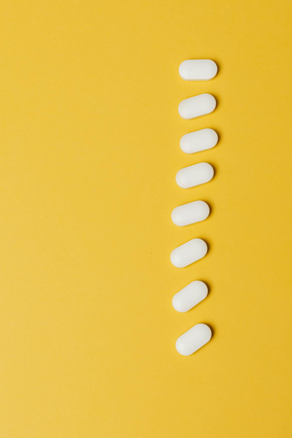 row of white pills on yellow background