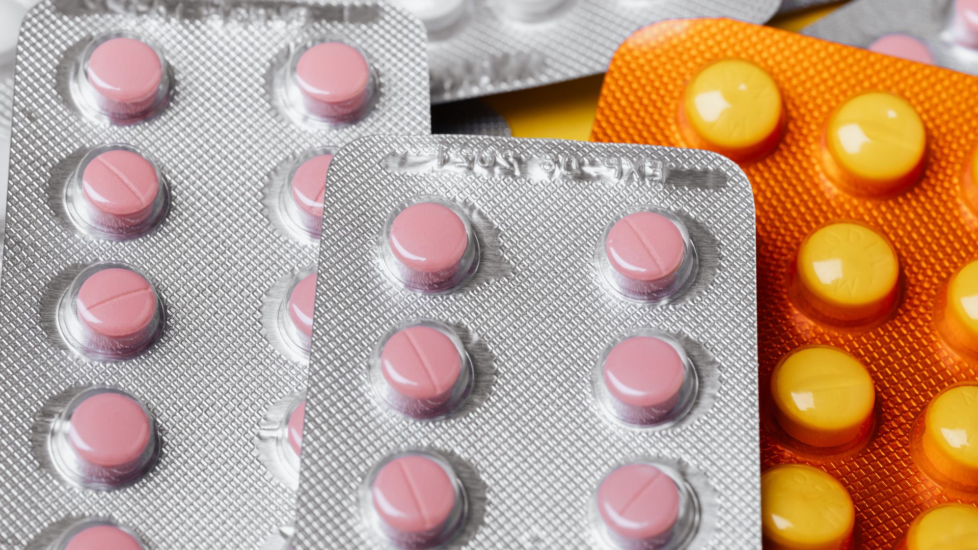 From above closeup of various multicolored pills of different sizes in plastic blister packs placed together under bright light — sun pharma modafinil