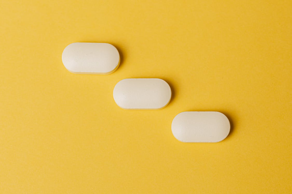 Prescription drugs or pills aligned on a yellow background. 