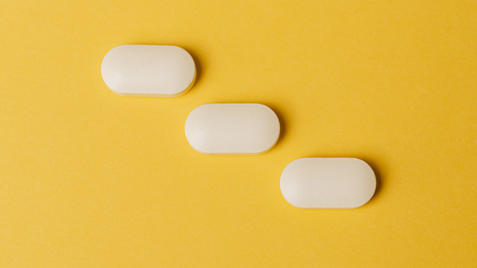 modafinil alertness: Guide Top view closeup composition of medical white pills placed diagonally on vivid bright yellow background — modafinil alertness