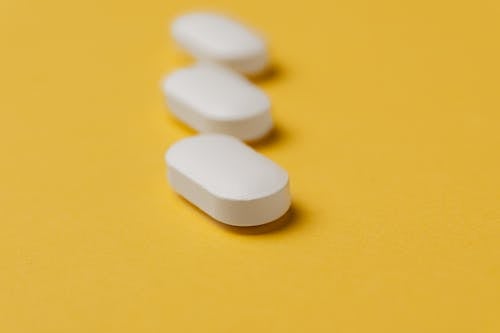 Set of white pills on yellow background