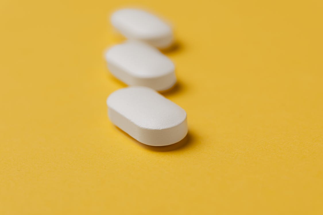 Free Set of white pills on yellow background Stock Photo