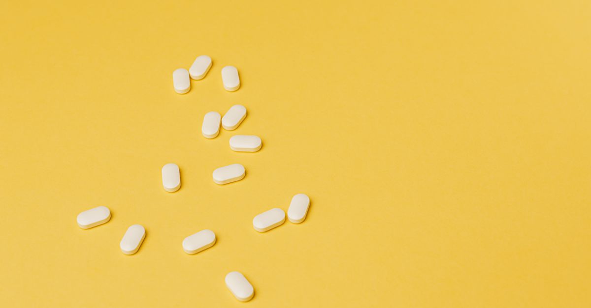 From above of small white ellipse shaped pills of same size randomly placed on bright yellow background - Evidence evidence guide for Coq10 Statin Fatigue Randomized Trial: What the Evidence Says