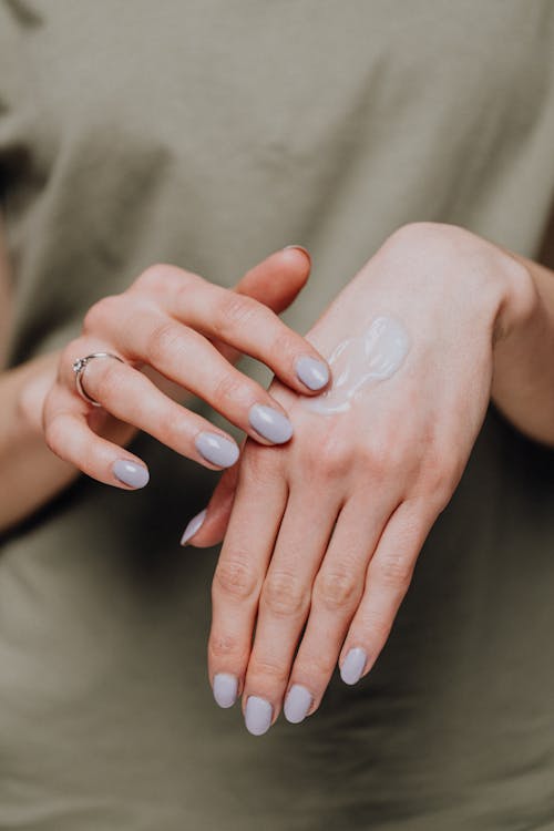 Free Crop woman applying cream on hands Stock Photo