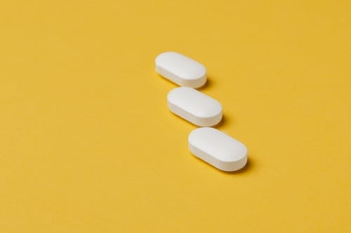 Set of white pills on yellow background
