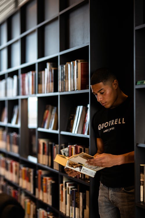 Concentrated black man reading book in library