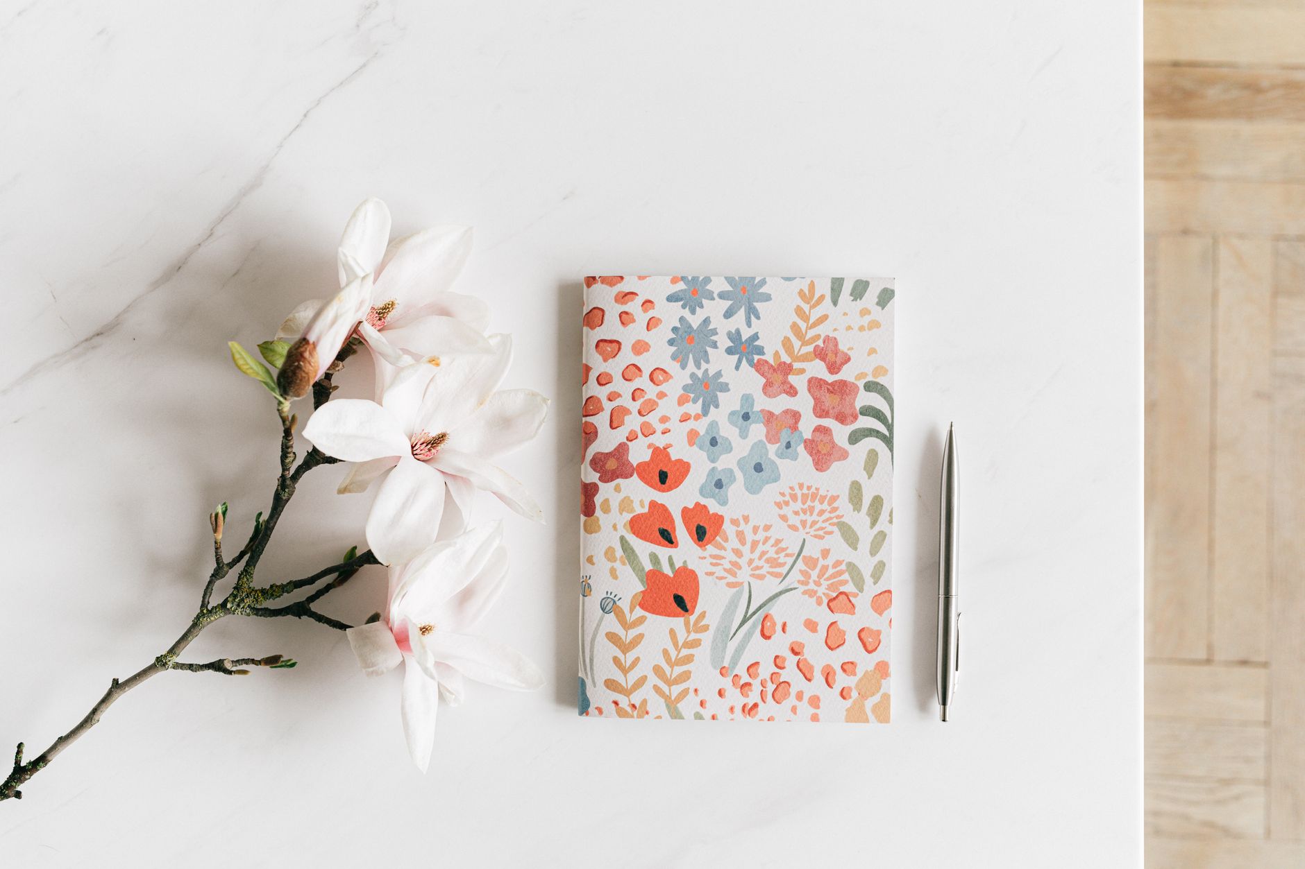 Notebook with pen near white Magnolia flower