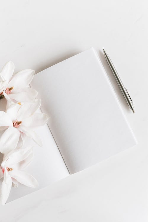 Free Opened notebook with silver pen near Magnolia Stock Photo