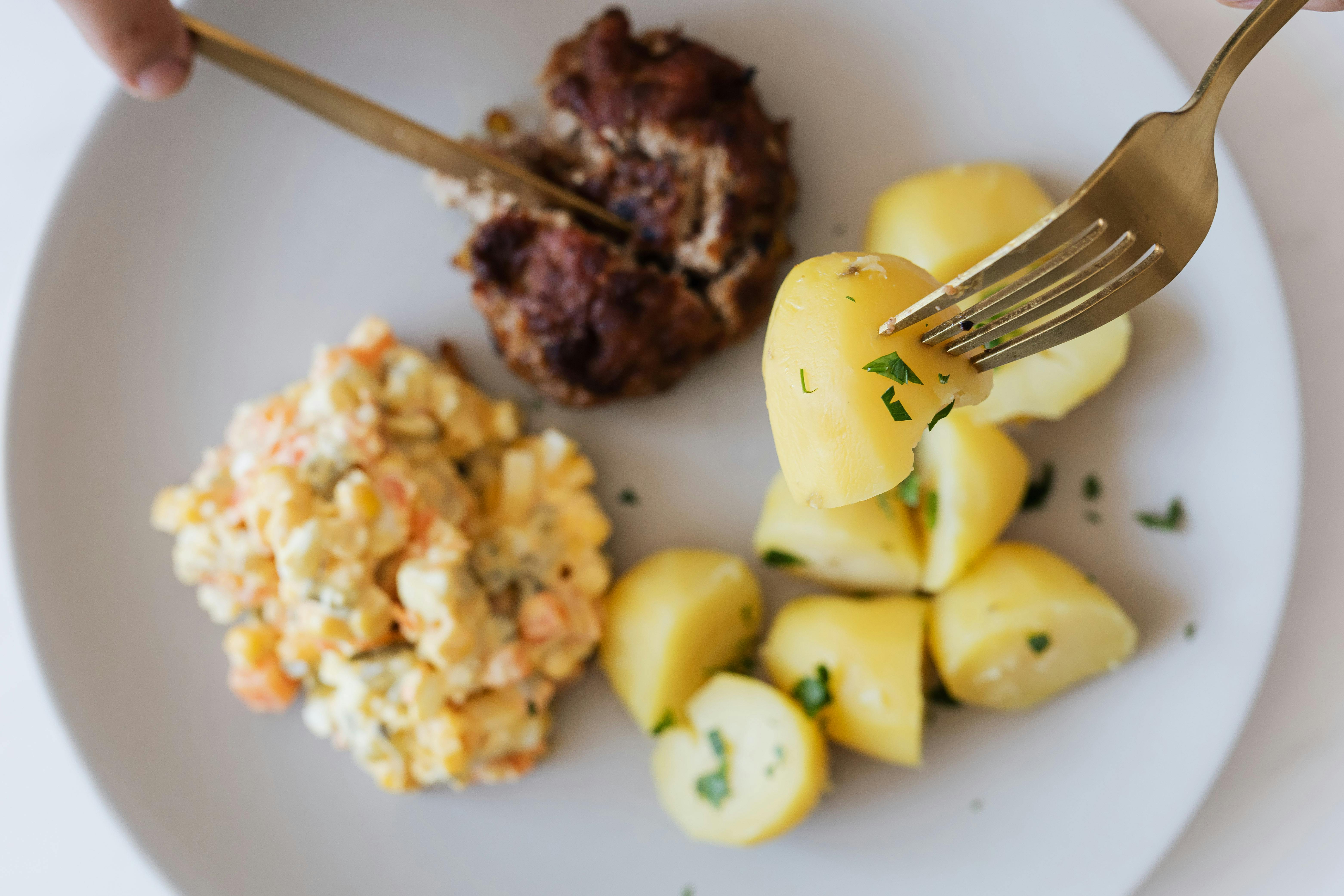 plate with boiled potatoes russian salad and meat cutlet