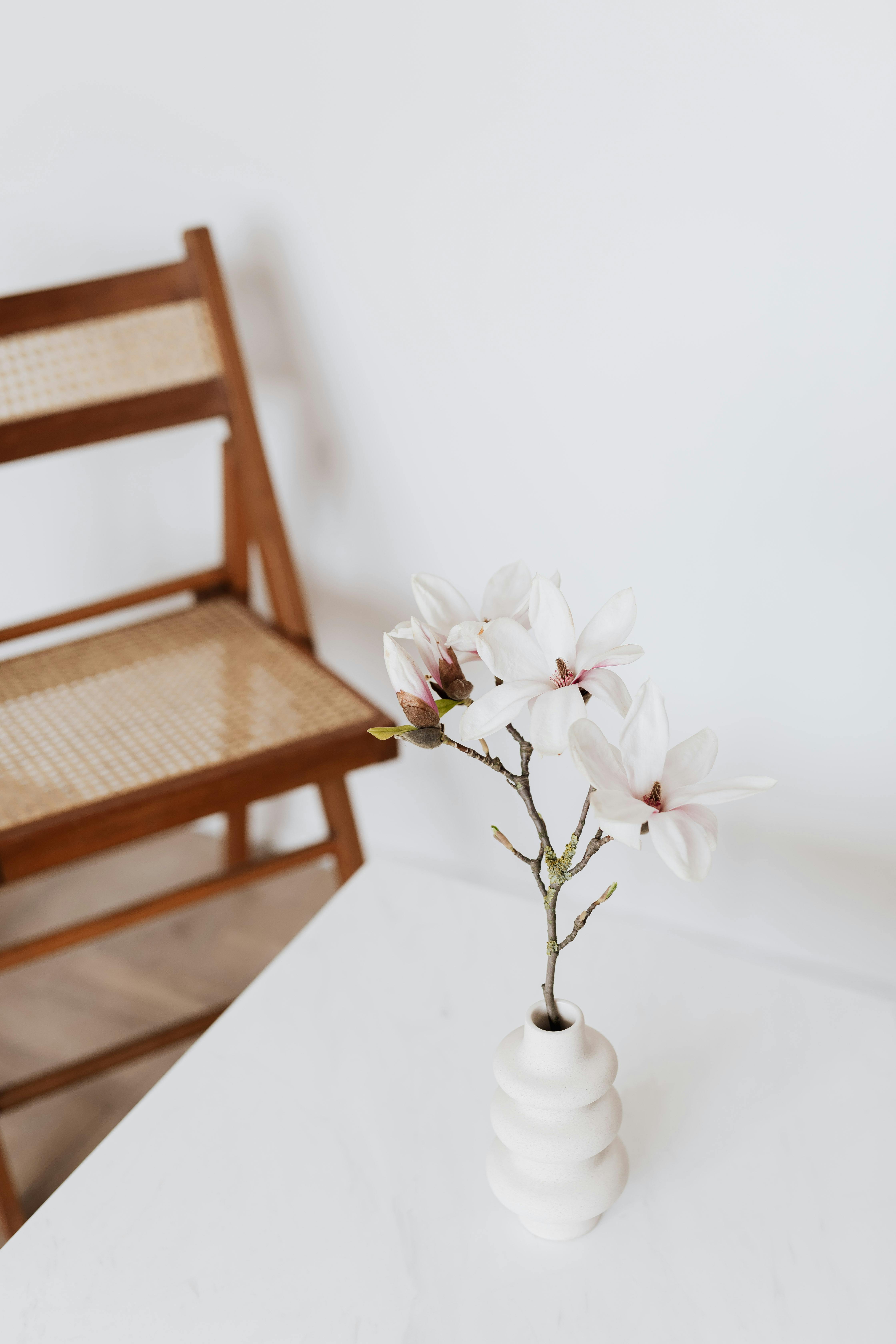 chair near table with vase and flower