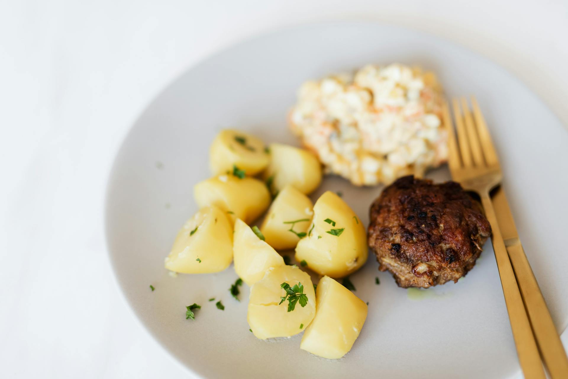 Fried meat cutlet served with boiled potatoes and salad