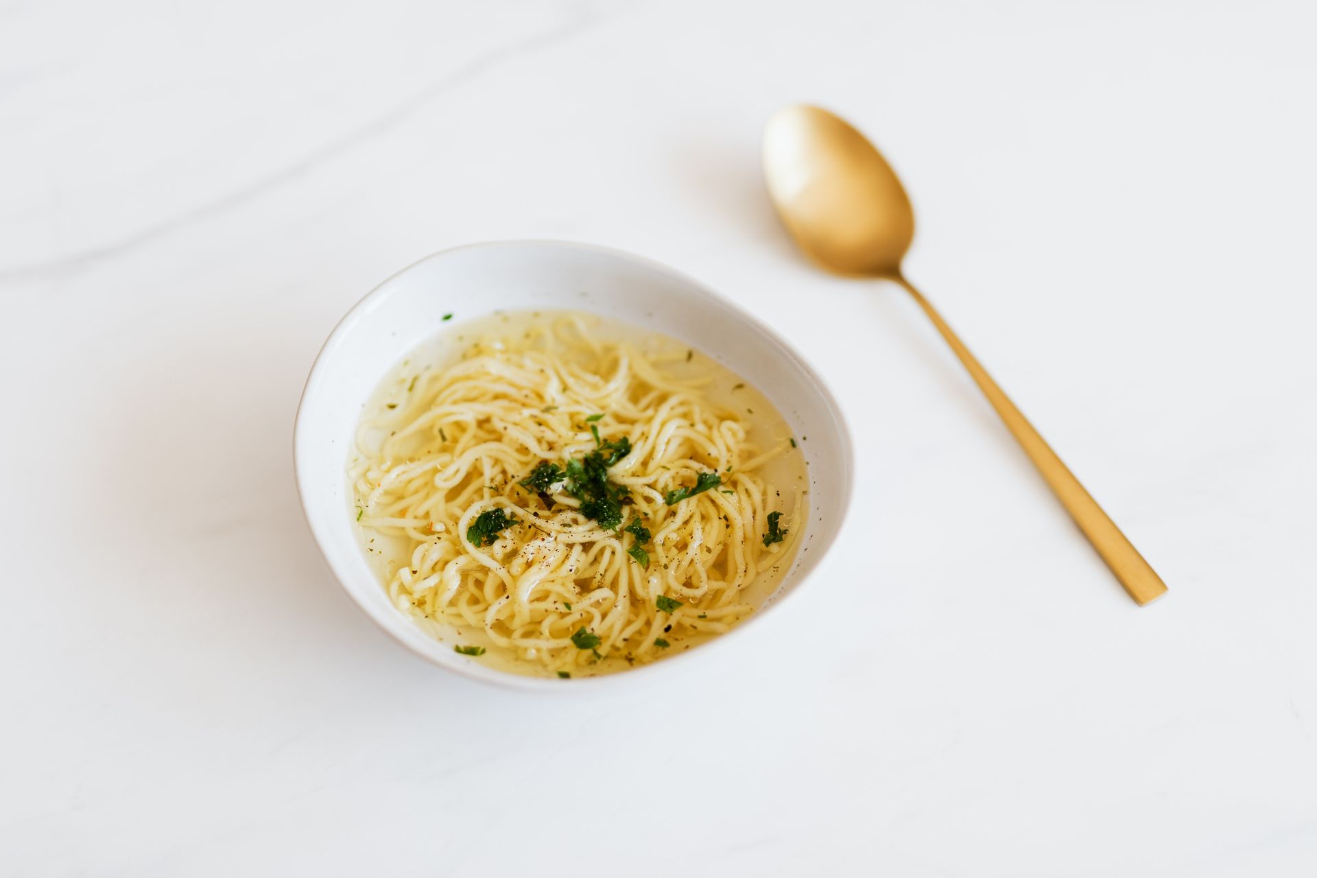 Bowl with tasty noodle soup near spoon