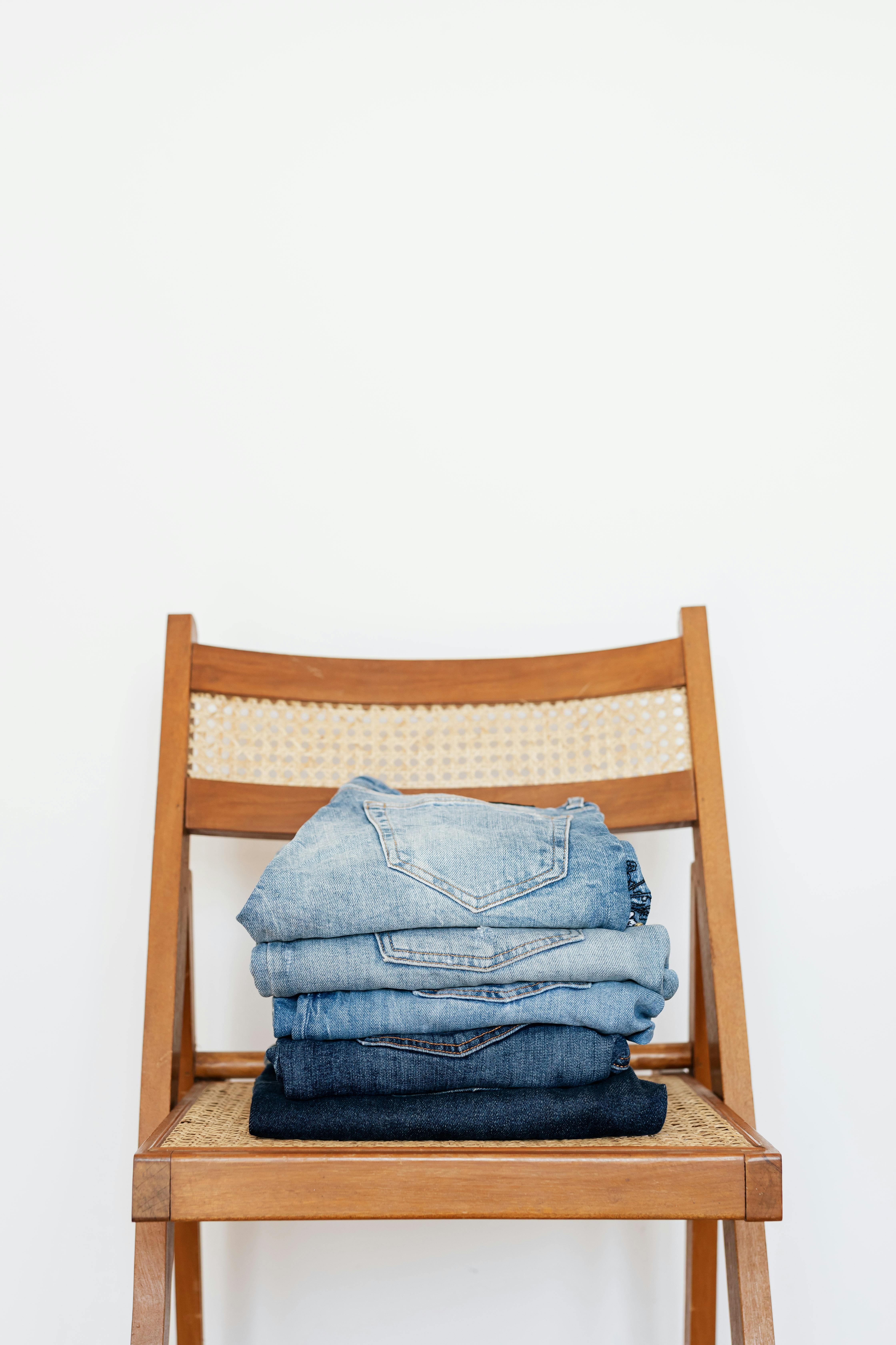 stack of blue jeans on chair