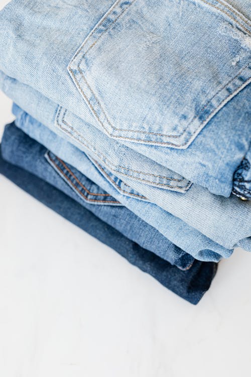 Stack of jeans on white marble surface