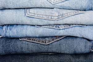 Closeup of stack of blue denim pants neatly arranged according to color from lightest to darkest