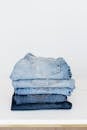 Pile of denim pants of different shades of blue placed on white shelf
