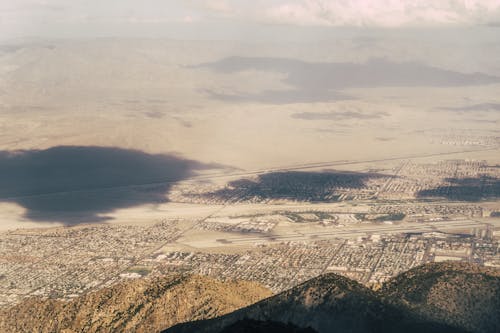 Aerial view of peaceful town located on desert terrain surrounded by hills and mountains on sunny day