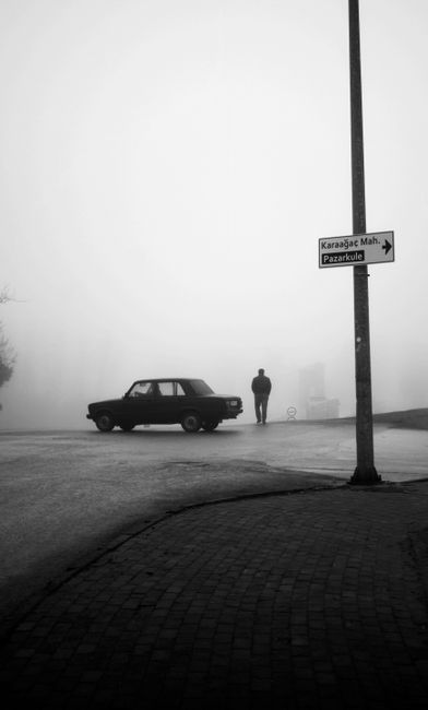 A mysterious silhouette and vintage car on a foggy street in Karaağaç, Edirne. Captivating monochrome atmosphere.