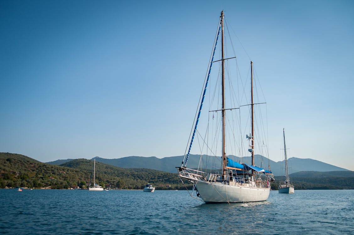 White and Black Boat Surrounded by Body of Water Under Blue Sky