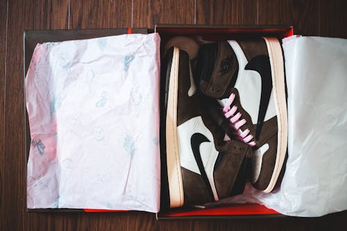 Free Top view of new stylish unisex sneakers in cardboard box placed on wooden floor Stock Photo
