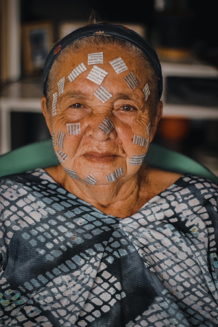 Elderly Woman With Small Stickers From Book On Face