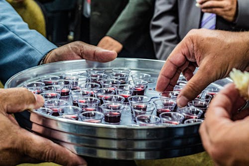 Free Crop anonymous male with metal tray full of small glasses of red wine for degustation Stock Photo