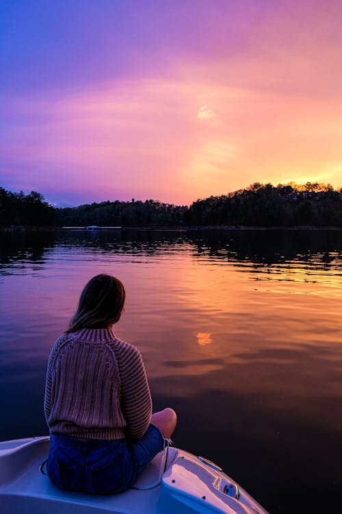 Free Photo of Woman Sitting on Boat While Looking at Sunset Stock Photo