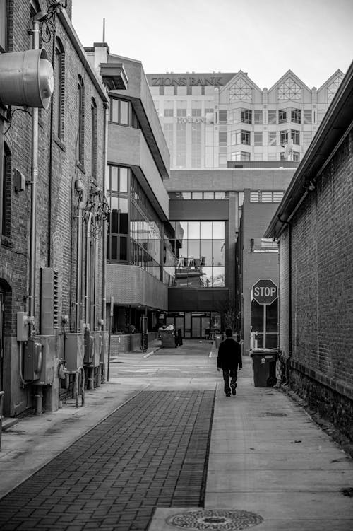 Grayscale Photo of Person Walking on Alley