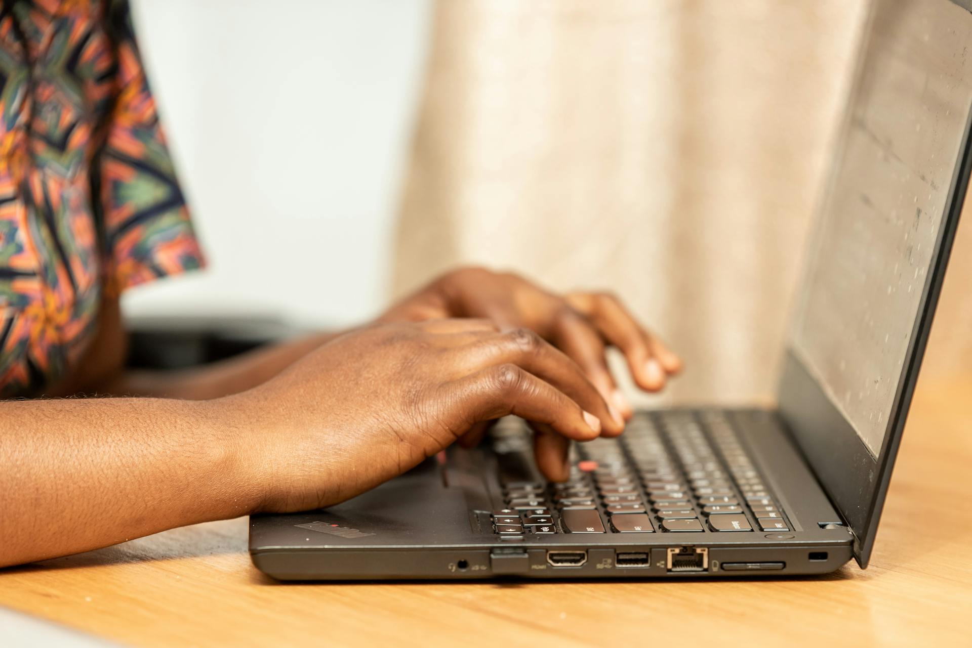 Detailed view of African hands typing on a laptop, shot indoors.