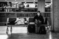 Anonymous tourists in masks on bench in airport