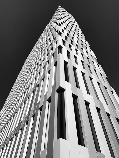 Low angle black and white of contemporary style multistory house facade with geometric walls under sky in town