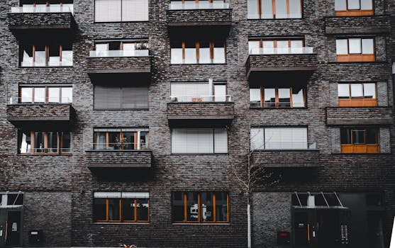 Brick facade of a modern urban apartment complex with balconies and windows, showcasing architectural design.