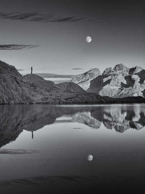 A man standing on the mountains with the moon 